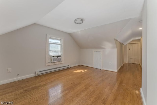 additional living space featuring a baseboard radiator, baseboards, wood finished floors, and vaulted ceiling