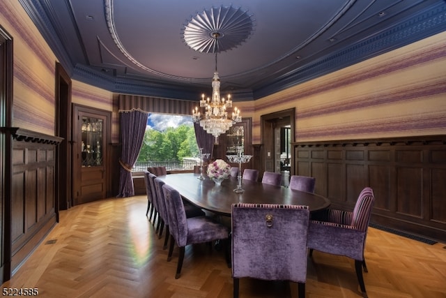 dining space with a raised ceiling, light parquet flooring, ornamental molding, and a chandelier