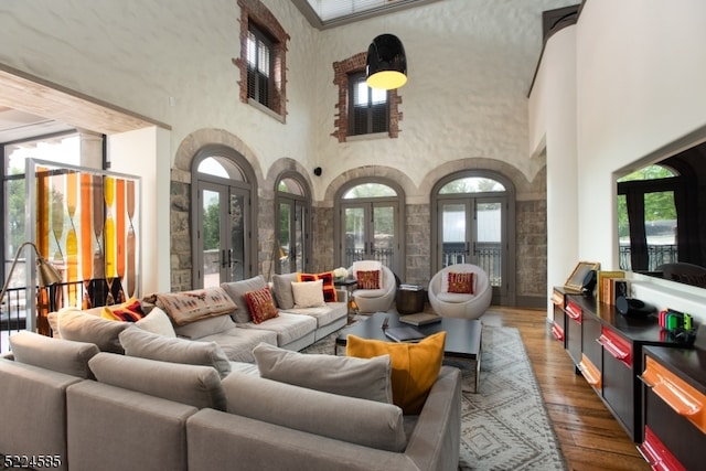 living room featuring a towering ceiling, dark wood-type flooring, and french doors