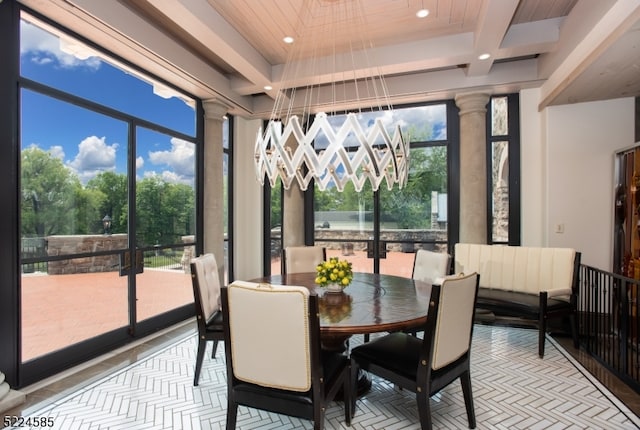 sunroom with coffered ceiling, a chandelier, and decorative columns