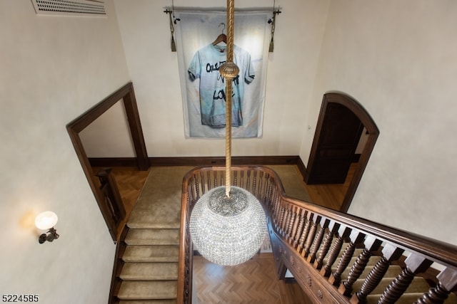 stairs featuring dark parquet flooring, a high ceiling, and a chandelier