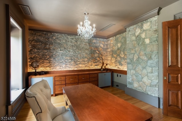 unfurnished dining area with light hardwood / wood-style flooring, crown molding, and a chandelier