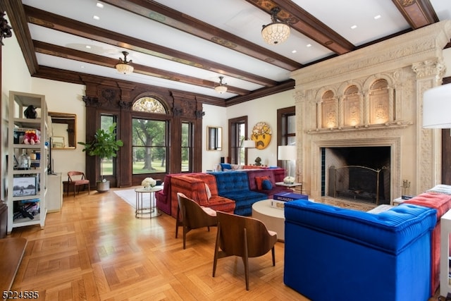 living room with light parquet floors, a large fireplace, ceiling fan with notable chandelier, beamed ceiling, and crown molding