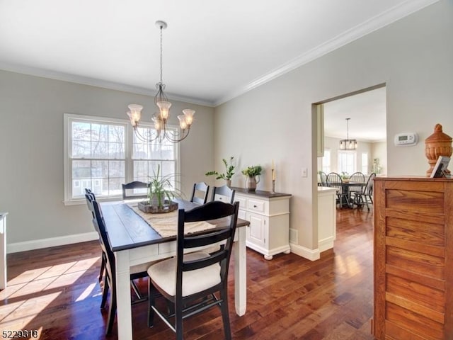 dining space with dark wood-type flooring, crown molding, baseboards, and a chandelier