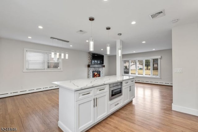 kitchen featuring built in microwave, a baseboard heating unit, a fireplace, a center island, and white cabinetry