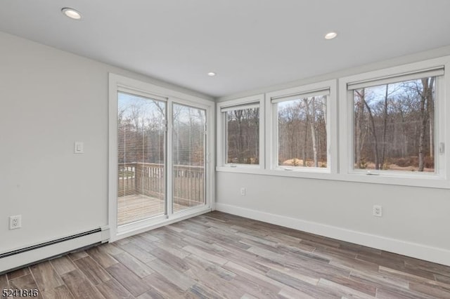 unfurnished sunroom featuring a baseboard heating unit