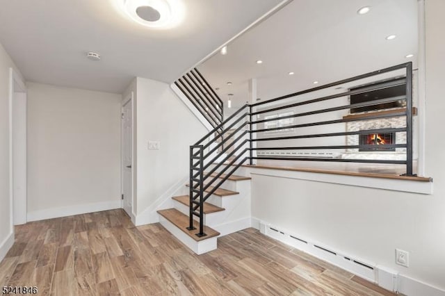 stairs with hardwood / wood-style floors and baseboard heating