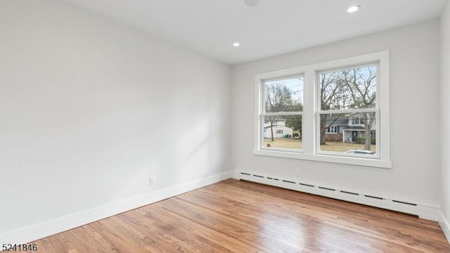 unfurnished room with wood-type flooring and a baseboard radiator