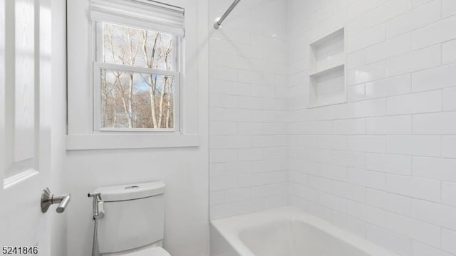 bathroom with a healthy amount of sunlight, toilet, and tiled shower / bath