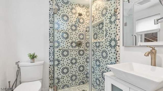 bathroom featuring vanity, toilet, and a shower with door