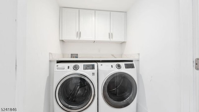 laundry room featuring washer and dryer and cabinets