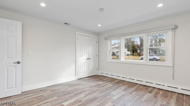 unfurnished room with light hardwood / wood-style floors and a baseboard radiator