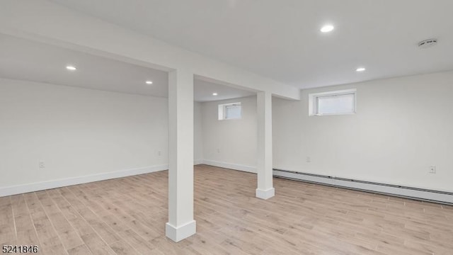 basement with a baseboard radiator and light hardwood / wood-style flooring