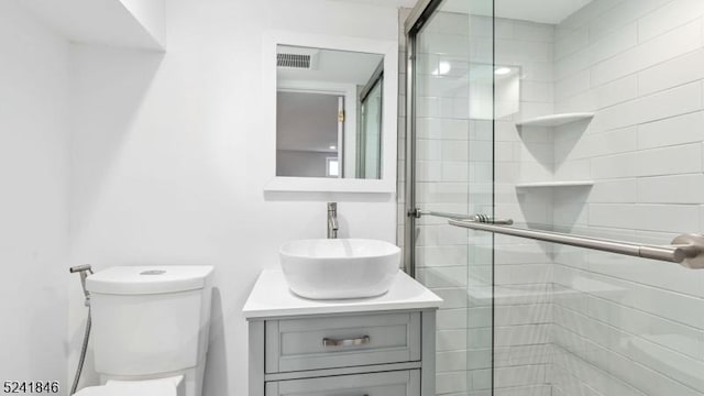 bathroom featuring vanity, toilet, and a shower with shower door