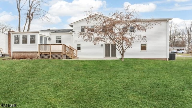 back of property featuring a sunroom, a deck, and a lawn