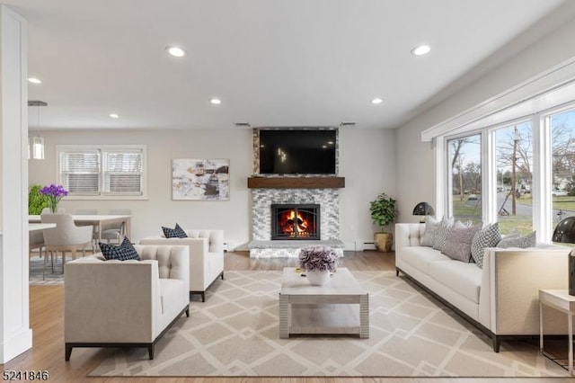 living room featuring a large fireplace, light hardwood / wood-style floors, and baseboard heating