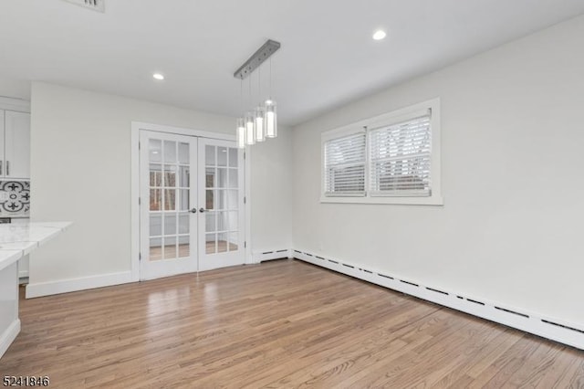 unfurnished dining area with light hardwood / wood-style floors, a baseboard heating unit, and french doors