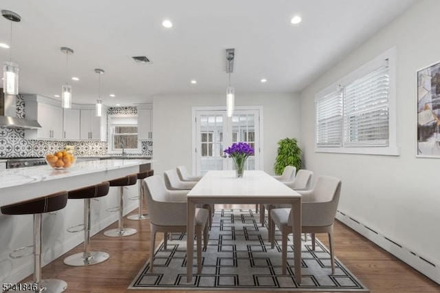 dining space featuring dark hardwood / wood-style floors, baseboard heating, and sink