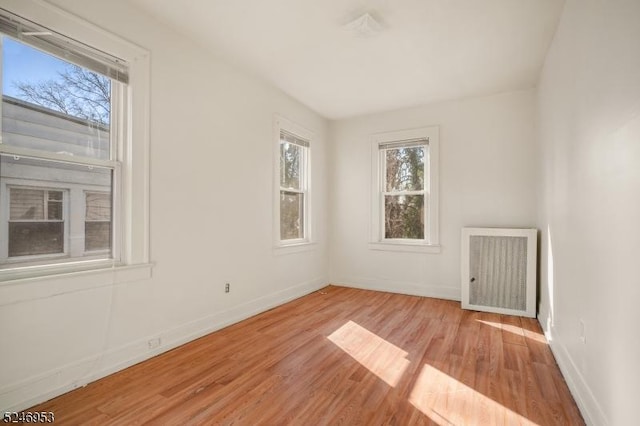 spare room with radiator, baseboards, and wood finished floors