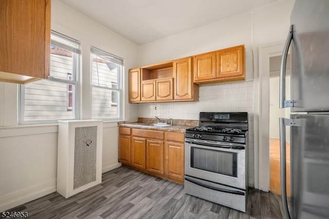 kitchen featuring tasteful backsplash, gas range, wood finished floors, freestanding refrigerator, and light countertops