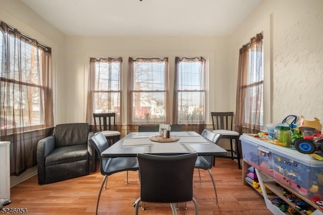 dining space featuring wood finished floors and a textured wall