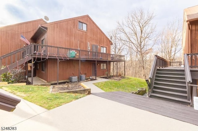 rear view of property featuring central AC unit, a yard, and a wooden deck