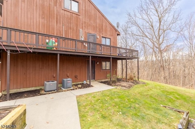 rear view of house featuring a lawn, cooling unit, and a deck