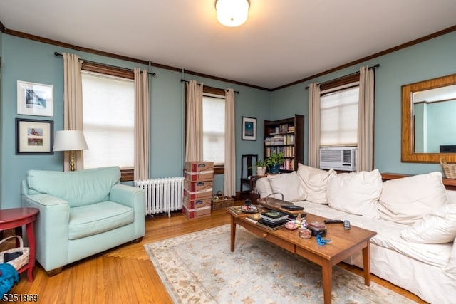 living room with radiator heating unit, light wood-type flooring, a wealth of natural light, and crown molding