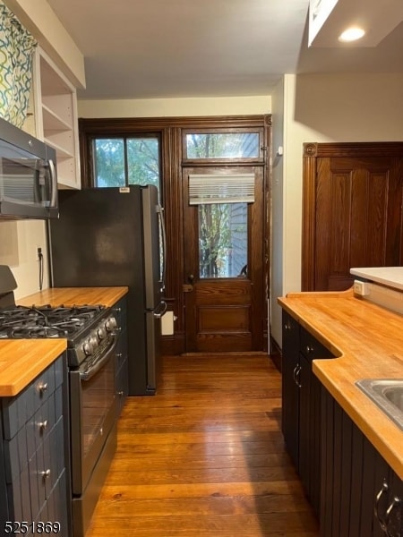 kitchen featuring black gas range, dark hardwood / wood-style flooring, and butcher block countertops