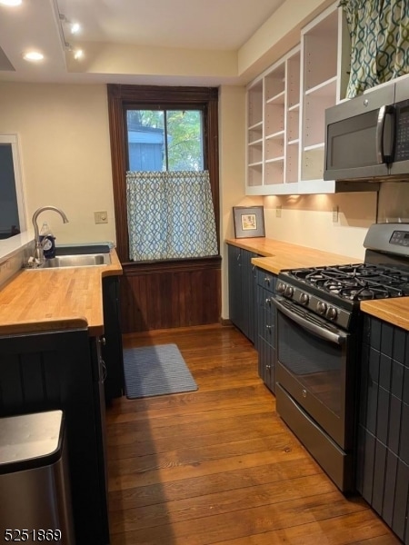 kitchen featuring sink, gas range oven, dark hardwood / wood-style flooring, butcher block counters, and track lighting