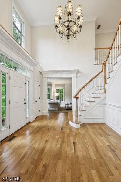 30 Clairvaux Ct, Bernards Twp, NJ 07920 - foyer entrance with stairway, a chandelier, wood finished floors, a towering ceiling, and crown molding