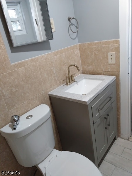 bathroom featuring toilet, vanity, backsplash, tile walls, and tile floors