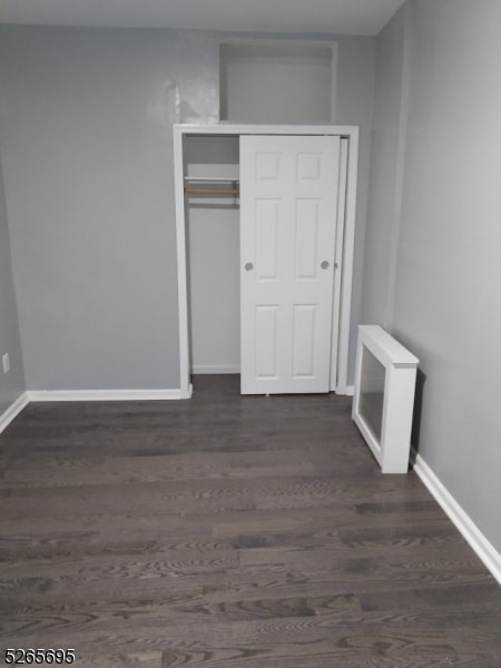 unfurnished bedroom with a closet and dark hardwood / wood-style flooring