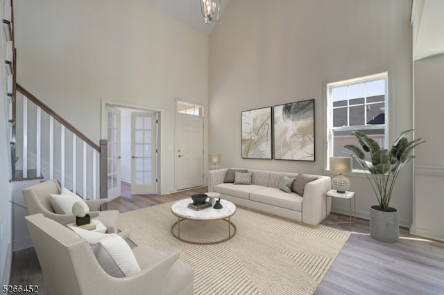 living room with an inviting chandelier, light hardwood / wood-style floors, and a towering ceiling