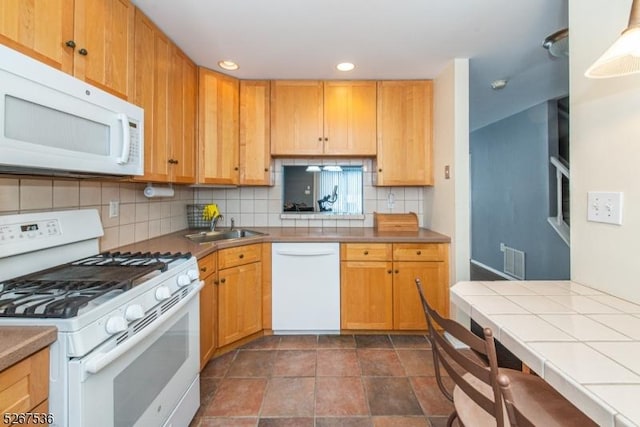 kitchen featuring white appliances, tile counters, visible vents, a sink, and backsplash