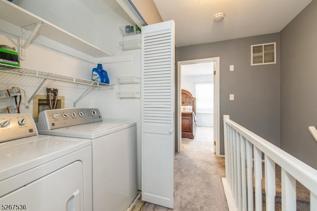 clothes washing area featuring washer and dryer, laundry area, visible vents, and light carpet