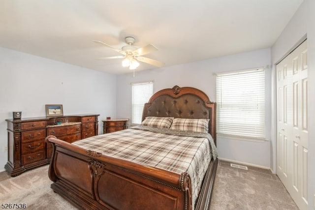 bedroom with light carpet, ceiling fan, baseboards, and a closet