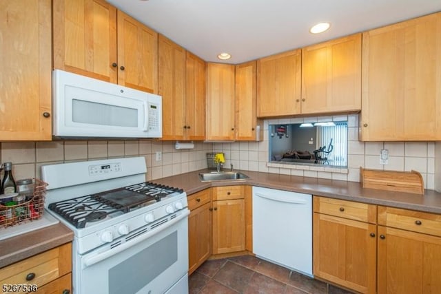 kitchen featuring dark countertops, white appliances, a sink, and decorative backsplash