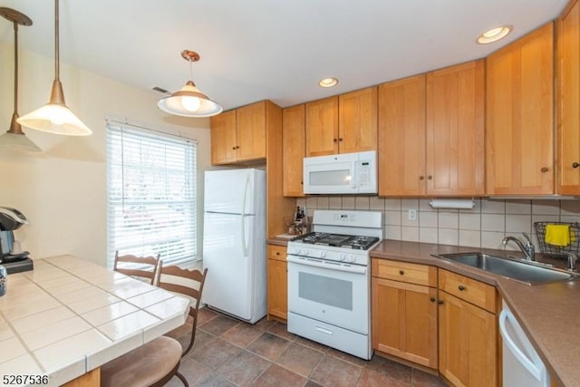 kitchen featuring white appliances, tile counters, decorative backsplash, and a sink