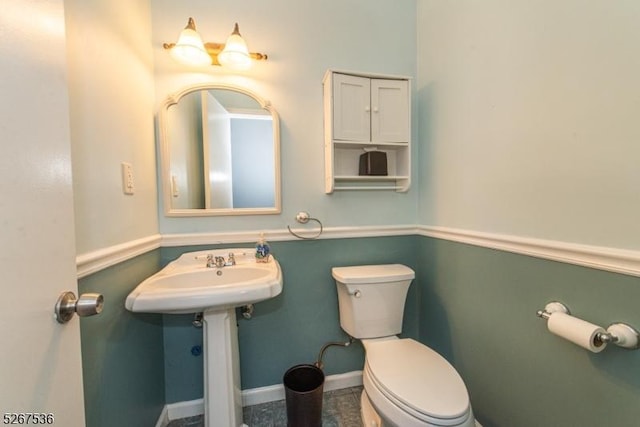 half bath with toilet, baseboards, and a sink