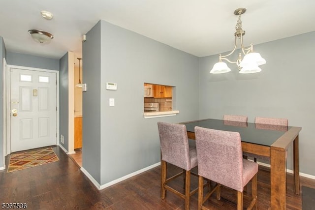 dining space featuring a chandelier, baseboards, and wood finished floors