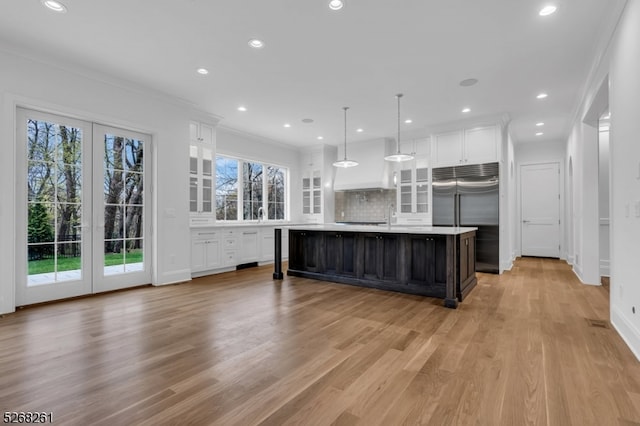 kitchen featuring white cabinets, a center island with sink, light hardwood / wood-style floors, and backsplash