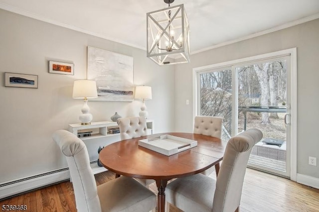 dining space featuring a chandelier, a baseboard heating unit, wood finished floors, baseboards, and ornamental molding