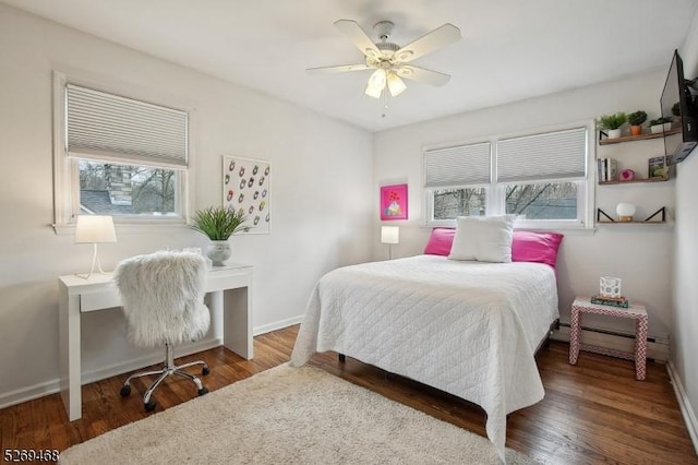 bedroom with a baseboard radiator, baseboards, and wood finished floors