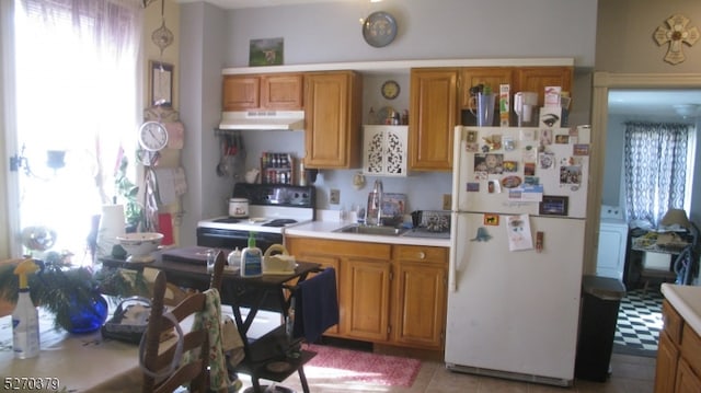 kitchen with washer / dryer, sink, white appliances, and a wealth of natural light