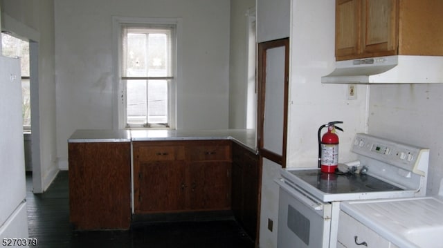 kitchen with plenty of natural light, dark wood-type flooring, electric range, and wall chimney exhaust hood