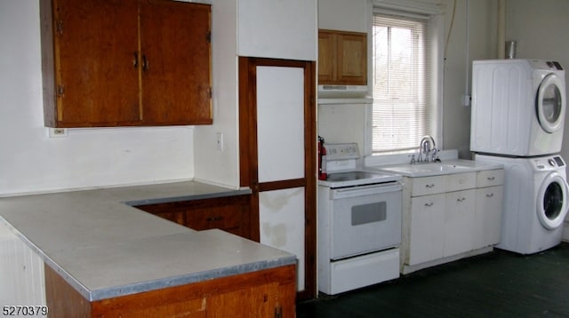 kitchen with white range with electric cooktop, wall chimney range hood, white cabinets, stacked washing maching and dryer, and sink