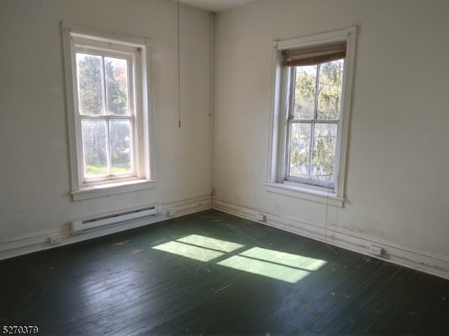 empty room featuring baseboard heating and dark hardwood / wood-style flooring