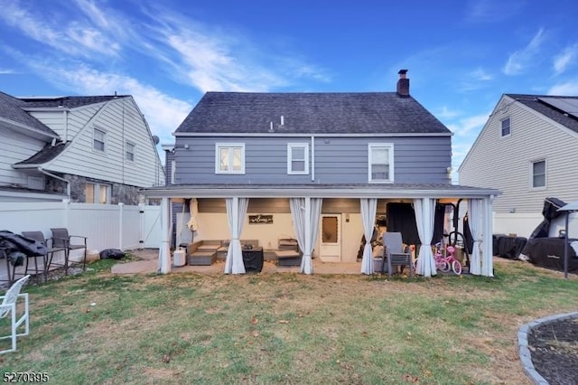 back of property featuring a lawn, an outdoor living space, and a patio