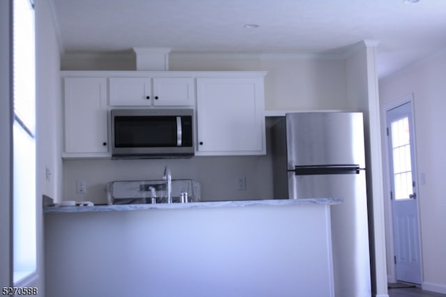 kitchen with white cabinets, light stone countertops, appliances with stainless steel finishes, and crown molding